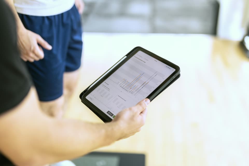 Zbliżenie na tablet w dłoni Karola z wykresem z testu skoku, w tle zawodnik